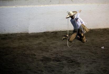 Carlos Maurer, de Puebla, practica suertes con el lazo durante una charreada en la Ciudad de México el 26 de febrero. La práctica del lazo consiste en colocar la cuerda tanto en el cuello como en las piernas de un toro mientras se monta a caballo. Las suertes con la cuerda puntúan extra.