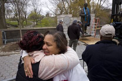 Dos mujeres se abrazan mientras funcionarios retiran la estatua del doctor Marion Sims de Central Park, Nueva York, el martes 17 de abril.