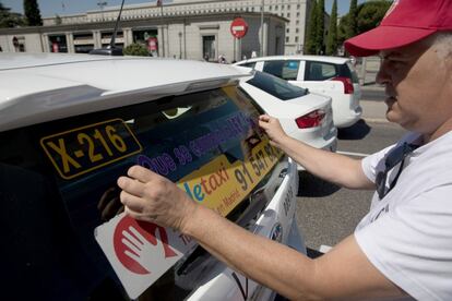 Un taxista coloca una pegatina que dice "que se cumpla la ley" en la parte trasera de su taxi durante las movilizaciones en Madrid frente al Ministerio de Fomento.