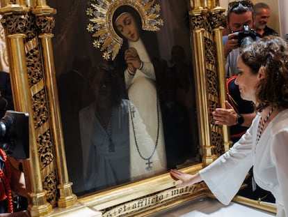 La presidenta de la Comunidad de Madrid, Isabel Díaz Ayuso, acaricia el cuadro de la virgen de la Paloma, en la iglesia de La Paloma y San Pedro el Real, en Madrid, este lunes.
