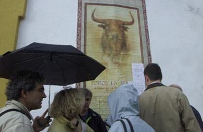 Aficionados, ante el cartel de la corrida de ayer, suspendida en la plaza de toros de la Maestranza.