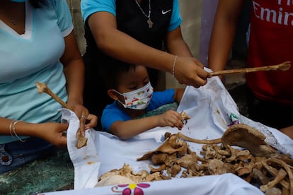 Con la idea de no olvidar a sus muertos y seguir teniéndolos cerca, los habitantes de Pomuch exhuman los restos, los limpian, los depositan en una caja de madera envueltos en un manto blanco y los colocan en un osario. En la imagen, un niño participa en la limpieza de huesos en Pomuch, el 31 de octubre de 2021.