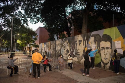 La gente busca su nombre en el padrón electoral y espera en la entrada de un colegio electoral.