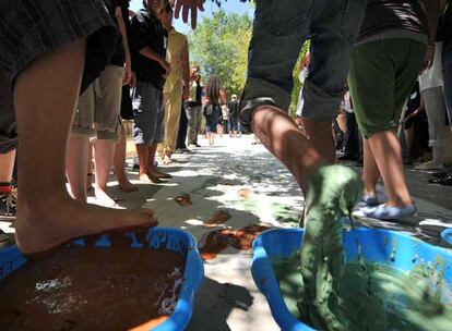 Un grupo de alumnos pinta con los pies un mural conmemorativo de la visita.