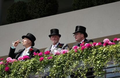 Tres caballeros beben champán desde uno de los palcos de Ascot.