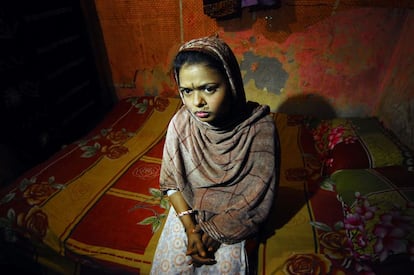 Asha, de 20 años, sentada sobre la cama en la que recibe una media de 5 clientes al día desde que tenía 9 años.