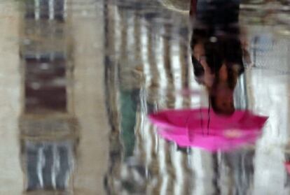 Reflejo de una mujer en un charco en una calle de Budapest, Hungría.