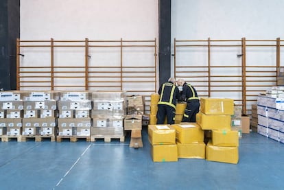 Dos trabajadores, en un gimnasio reconvertido en almacén de material sanitario.