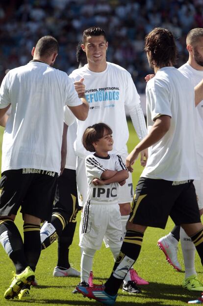 Zaid Abdul, el niño refugiado sirio, en el césped del Santiago Bernabéu vestido con la equipación del Real Madrid junto a Cristiano Ronaldo (c) antes del partido que el equipo disputa frente al Granada.