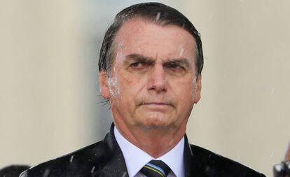 Brazilian President Jair Bolsonaro is drenched with rain during a downpour as he attends a ceremony to mark Army Day, in Brasilia on April 17, 2019, two days ahead of the actual celebration date. (Photo by Sergio LIMA / AFP)