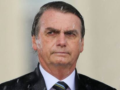 Brazilian President Jair Bolsonaro is drenched with rain during a downpour as he attends a ceremony to mark Army Day, in Brasilia on April 17, 2019, two days ahead of the actual celebration date. (Photo by Sergio LIMA / AFP)