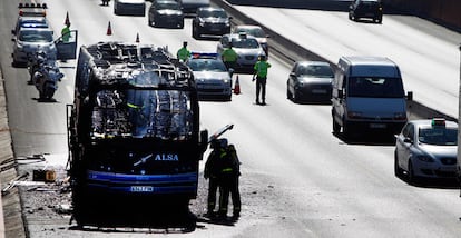 Los restos del vehículo, de la empresa ALSA, son inspeccionados por efectivos de los bomberos.