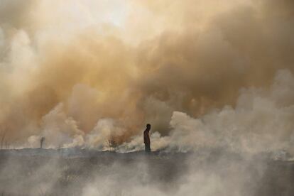Un oficial camina hacia un fuego en cuya extinción trabajan los bomberos, cerca de Palembang (Indonesia).