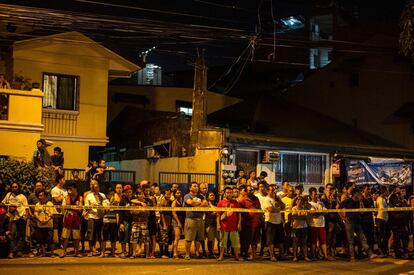 Residentes de Manila detrás de un cordón policial mirando los cadáveres de varios narcotraficantes fallecidos en un tiroteo con la policia filipina en una operación de incautación de droga.