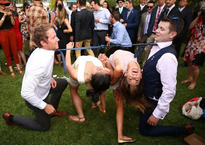 Dos mujeres se inclinan durante el juego del limbo durante la Copa del Día de Melbourne 2015 en el hipódromo de Flemington (Australia).