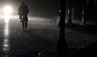 Un ciclista circula por la carretera de noche y con lluvia.