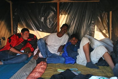 Tres jóvenes dentro de una tienda de campaña en la explanada de Velika Kladusa donde se concentran cientos de migrantes y refugiados.