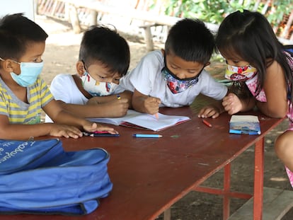 Cuatro alumnos hacen sus deberes al aire libre en una de las clases que se imparten de manera informal en un barrio de Guayaquil.