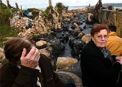 Vecinos de Camelle contemplan en el puerto de la localidad coruñesa los efectos de la mancha de fuel vertida por el petrolero <b></b><i>Prestige.</i>