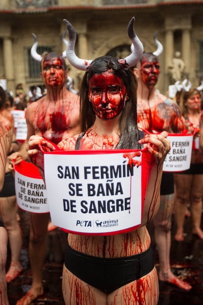 Una de las asistentes sostiene un cartel con el lema 'Sanfermin se baña de sangre', en la protesta que hoy martes ha tenido lugar en Pamplona contra el maltrato animal en este fiesta popular.