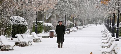 Un hombre pasea por el parque de la Alamdeda de Soria cubierto por la nieve.