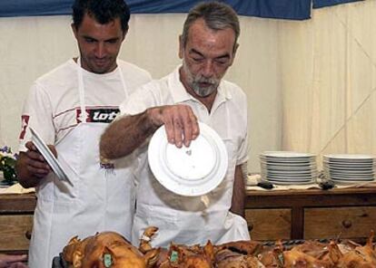 Quino Muñoz e Ignacio Salas partiendo el cochinillo con un plato, al modo tradicional.