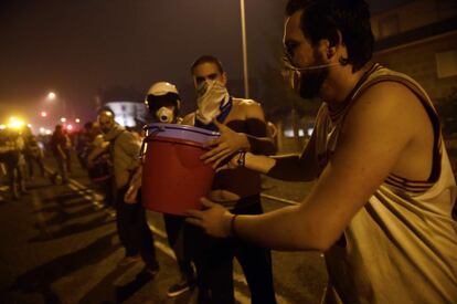 Un grup de persones formen una cadena humana per transportar galledes d'aigua per ajudar a combatre un incendi forestal a Vigo.