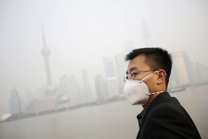 Un turista se protege con una mascarilla de la contaminación al fondo se ven envueltos en una bruma los edificios del Bund de Shanghai, China. La Oficina de Protección Ambiental de Shanghai emitió una alerta de contaminación `amarilla´, recomendando que los niños, ancianos y las personas que sufren de enfermedades del corazón o enfermedad pulmonar deben quedarse en casa y evitar hacer ejercicio al aire libre.