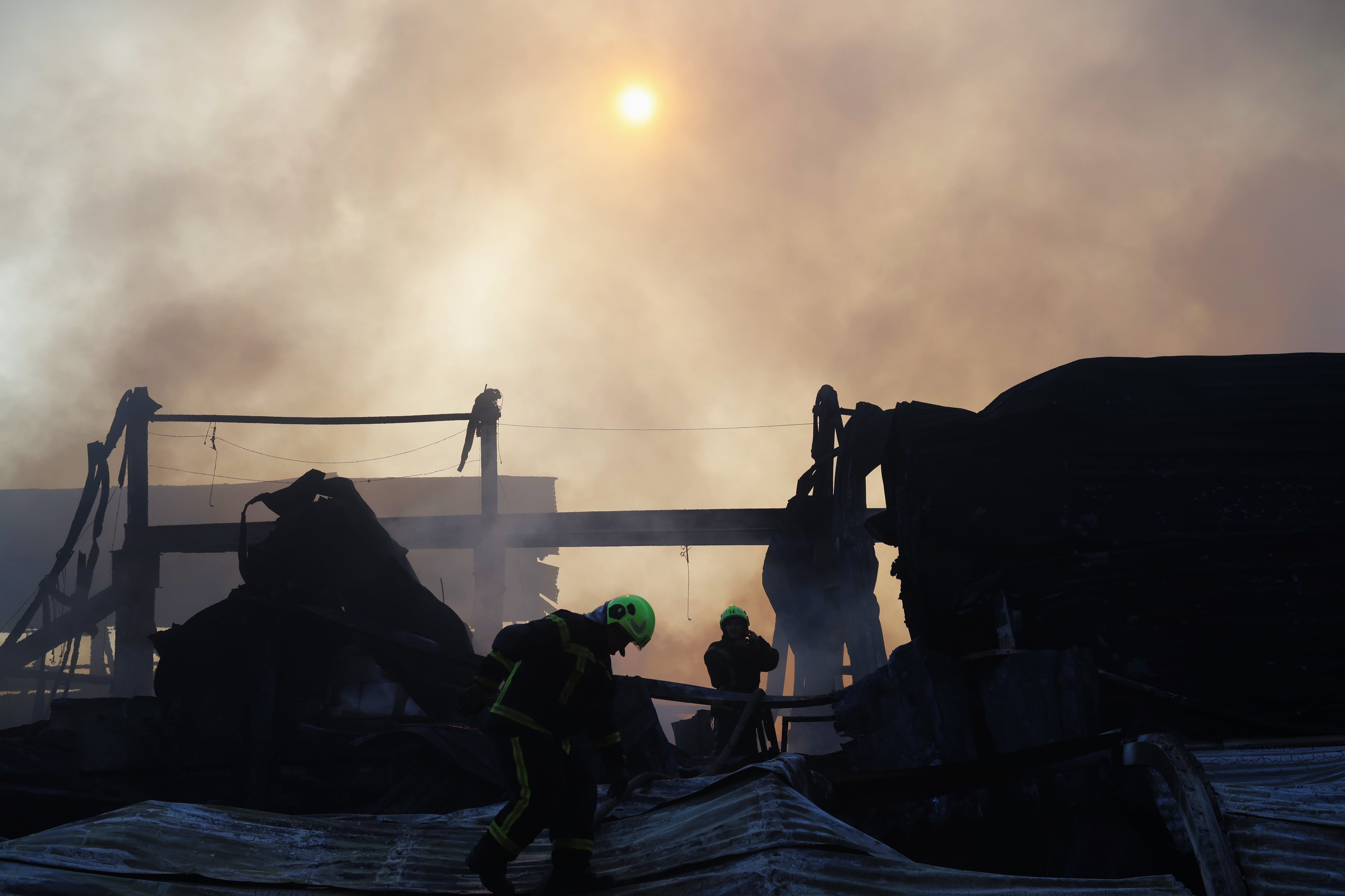 Los bomberos sofocan las llamas tras el impacto de dos misiles en luna zona industrial de Podil, Kiev, este miércoles.
