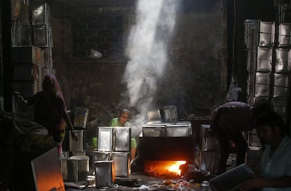 Trabajadores limpian latas de aceite de cocina usados en un taller de reciclaje en Mumbai (India).
