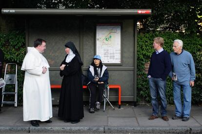 Una monja se encuentra con un hombre del clero en una parada de autobús cerca de St Mary's University College en Twickenham.