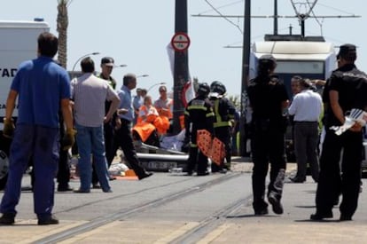 Bomberos y sanitarios rodean el coche en el que fallecieron dos hombres al ser arrollados por un tranvía.