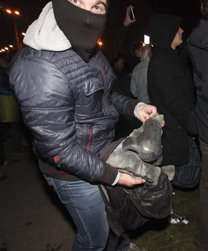 Un manifestante enseña un trozo de la cara de la estatua de Lenin, antes de guardarla en su mochila.