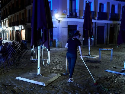 Una trabajadora recoge la terraza de una cafetería de Madrid pasada la medianoche.