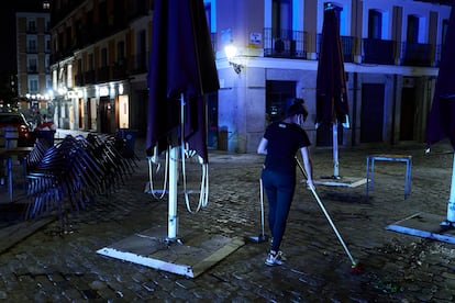 Una trabajadora recoge la terraza de una cafetería de Madrid pasada la medianoche.