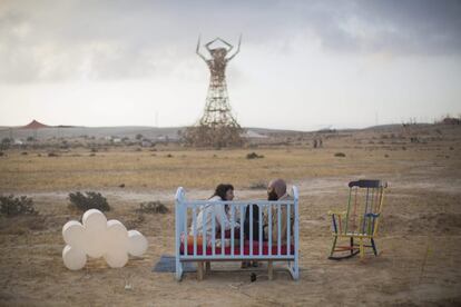 Una cuna instalada en medio del desierto Negev, donde se ha establecido esta comunidad artística temporal, sirve de asiento a una pareja que charla frente a la escultura de madera que representa un hombre y que será quemada para concluir los cinco días de arte y convivencia.