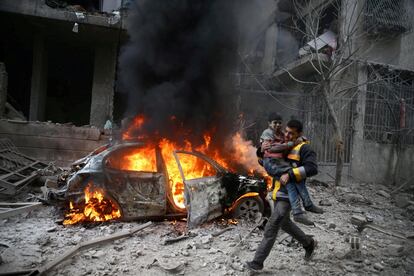 Un miembro de la defensa civil de Siria lleva en brazos a un niño herido tras un ataque aéreo del régimen de Al Asad sobre la ciudad de Hamoria, al este de Guta, el 6 de enero de 2018. Según el Observatorio Sirio de Derechos Humanos, una ONG con sede en Londres que monitoriza el conflicto de aquel país, los ataques aéreos y el fuego de artillería del Ejército sirio dejaron un saldo de 24 personas fallecidas, incluidos 10 menores. Desde que se desataron las hostilidades en 2011, la guerra siria se ha cobrado la vida de más de 500.000 personas.