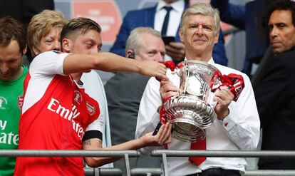 Mesut Özil le entrega el trofeo a Arsène Wenger.