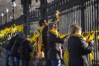Manifestantes independentistas cuelgan lazos amarillos en las verjas del parque de la ciudadela por los políticos que están en prisión durante la votación para constituir la mesa del Parlament.