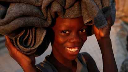 Un niño sonrie mientras lleva una manta en la cabeza, en Jérémie (Haití).