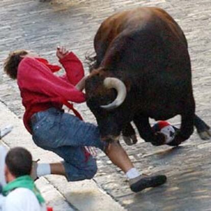El toro que abría la manada lanza un derrote contra un mozo que evitó la cornada providencialmente. Éste fue el momento más peligroso del encierro de hoy.