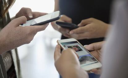 Un grupo de chicas usa sus teléfonos móviles. 