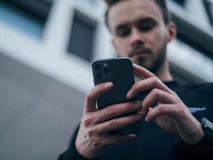 Un hombre mira un teléfono móvil.