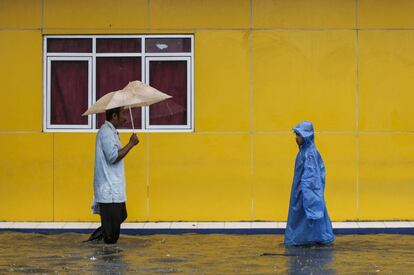 Varios residentes de la ciudad de Yakarta (Indonesia) caminan por las aguas que han dejado las inundaciones. La ciudad fue golpeada por las inundaciones generalizadas este martes después de horas de lluvias torrenciales dejando miles de hogares inundados, coches varados y personas forzadas a caminar a través del agua cenagosa.