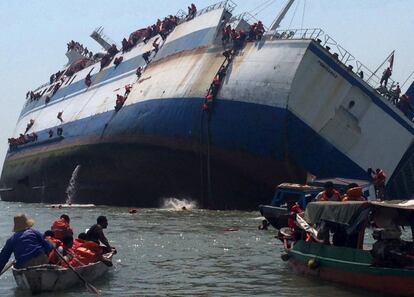 Pasajeros son evacuados por uno de los lados del transbordador KM Wihan después de volcar en el puerto deTanjung Perak, en Java Oriental.