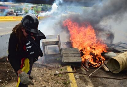 Un manifestante pasa por una barricada improvisada incendiada durante una protesta contra el presidente venezolano Nicolás Maduro, en Caracas (Venezuela).