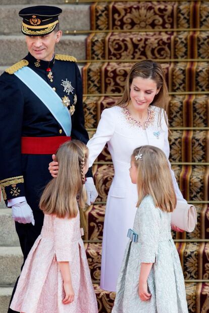 Los Reyes junto a sus hijas durante la coronación, el 19 de junio de 2014. Natural y sencilla, Doña Letizia hace un gesto de cariño a la princesa Leonor y a la infanta Sofía, que iban conjuntadas con el mismo vestido en diferentes tonos.