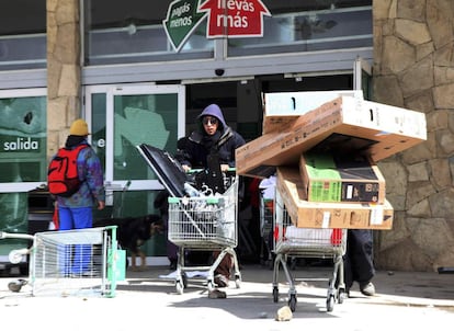 Varias personas extraen mercancía del supermercado Chango Mas, en la ciudad de San Carlos de Bariloche, Argentina.