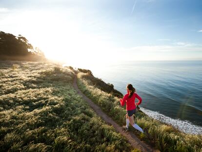 A woman runs by the ocean.