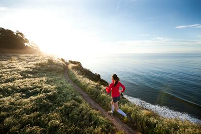 A woman runs by the ocean.